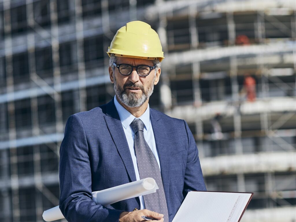 Chartered surveyor on a construction site holding plans